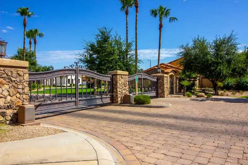 Ornate driveway gate of a gated community with professional landscaping