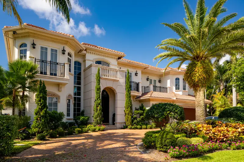 Multi-story luxury estate showcasing dense, colorful garden landscaping.