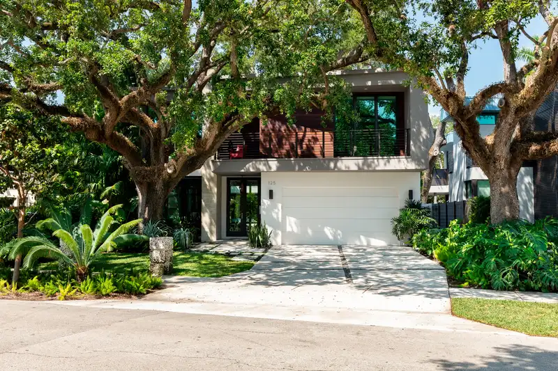 Modern home featuring lush tropical landscaping and professional tree care